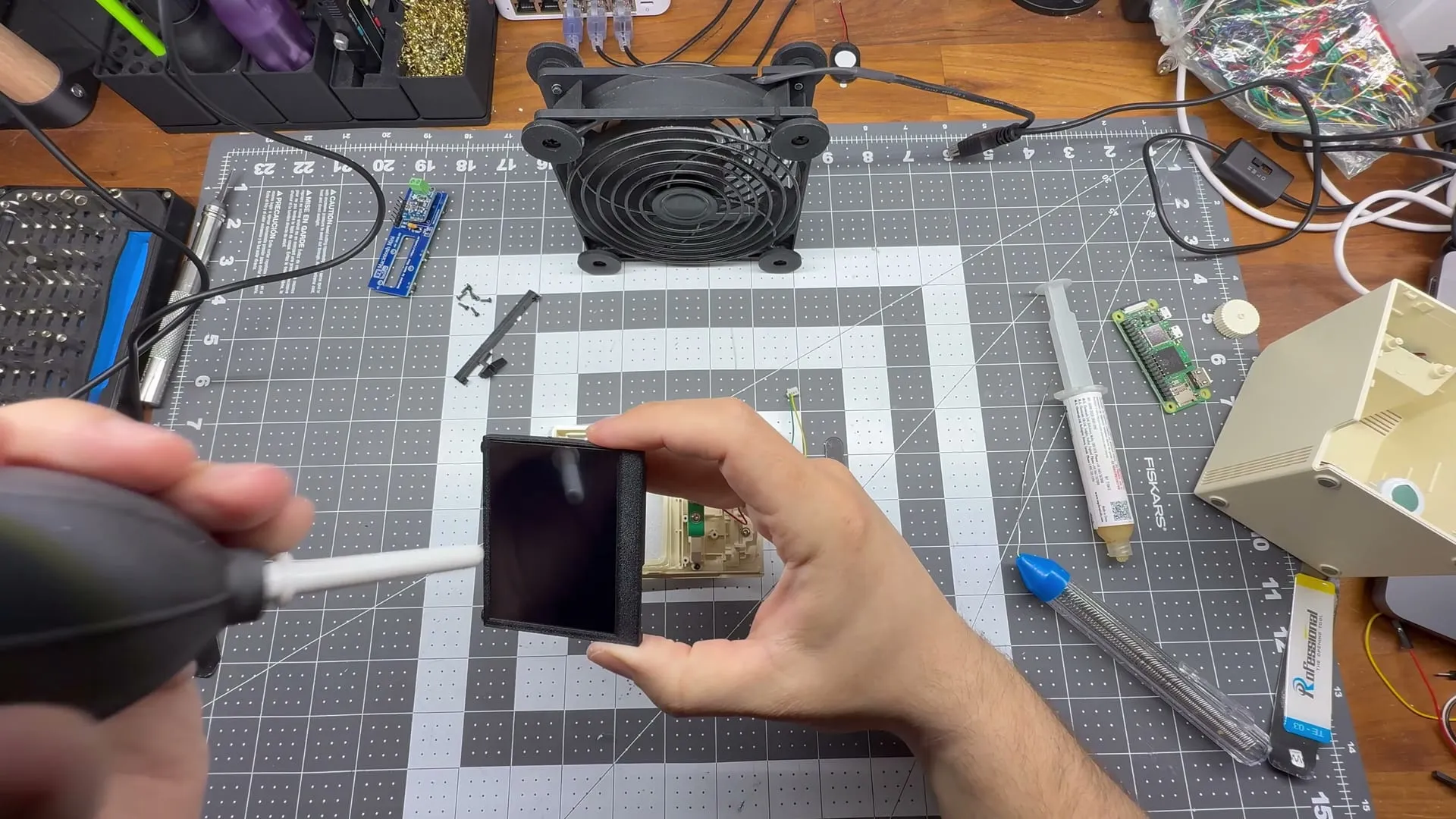 Cleaning the new display with an air blower before fitting it