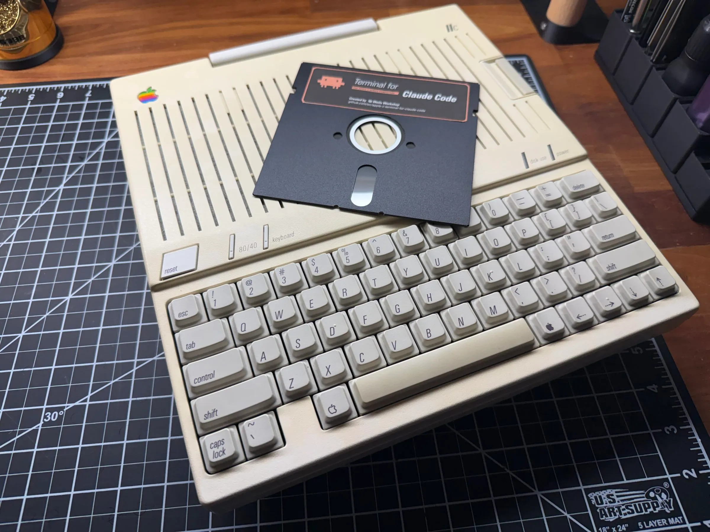The Terminal for Claude Code floppy disk on an Apple IIc's keyboard