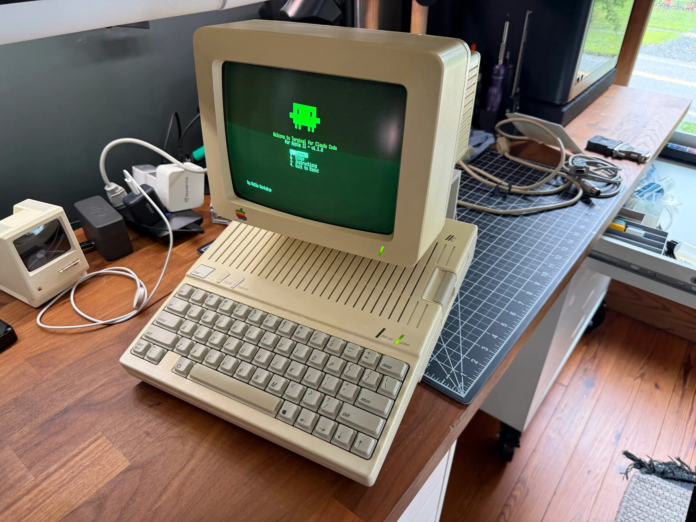 An Apple IIc and its monitor on a desk, at the Terminal for Claude Code menu